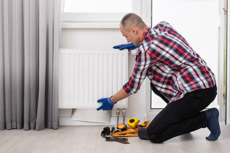 Local plumber inspecting a radiator at a West Midlands property