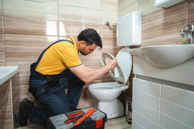 Local plumber repairing a toilet at a North West property